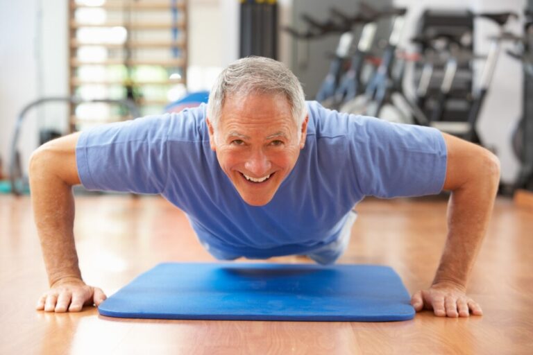 An old man, doing a push up with a smile. age 50+ fitness